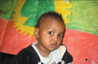 A child from the Oromo Community sitting behind the Oromo flag. YT PHOTO BY MOHAMMED AL-JABRI