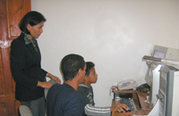 Ramzy showing Fares how to lay out the page with teacher Zalino observing.