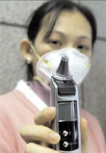 A Taiwanese nurse wields an electronic thermometer at the arrival hall at Taipei international airport, April 10. (Reuters)