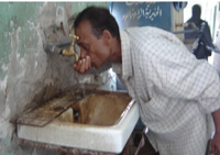 A nurse drinks directly from the tap of a rusty basin. The hospital also experiences constant water cuts.